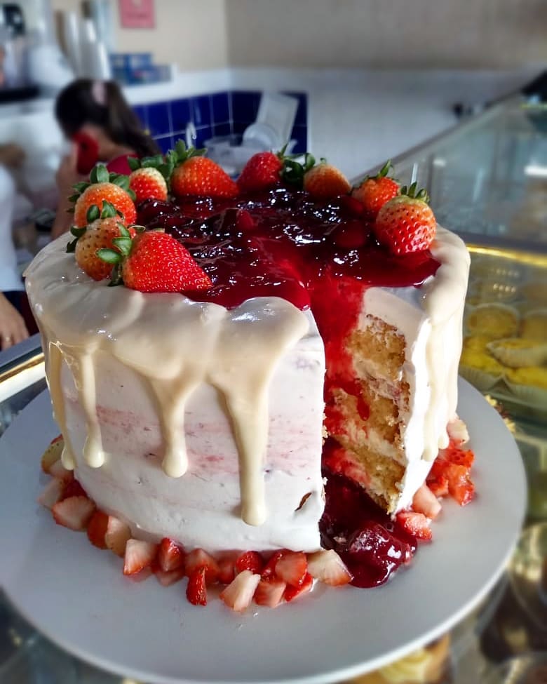 Bolo com cobertura branca e frutas vermelhas